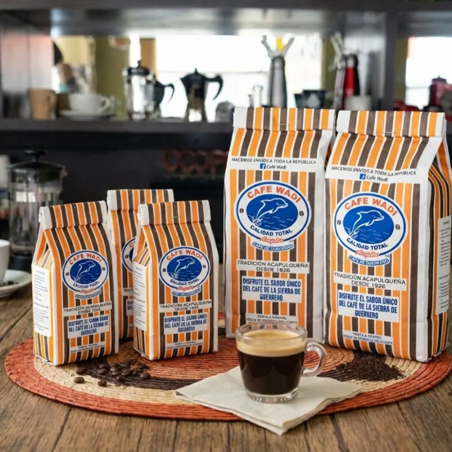 Cinco bolsas de Café Wadi con las franjas naranjas y cafés de la marca, junto a una taza de espresso servida